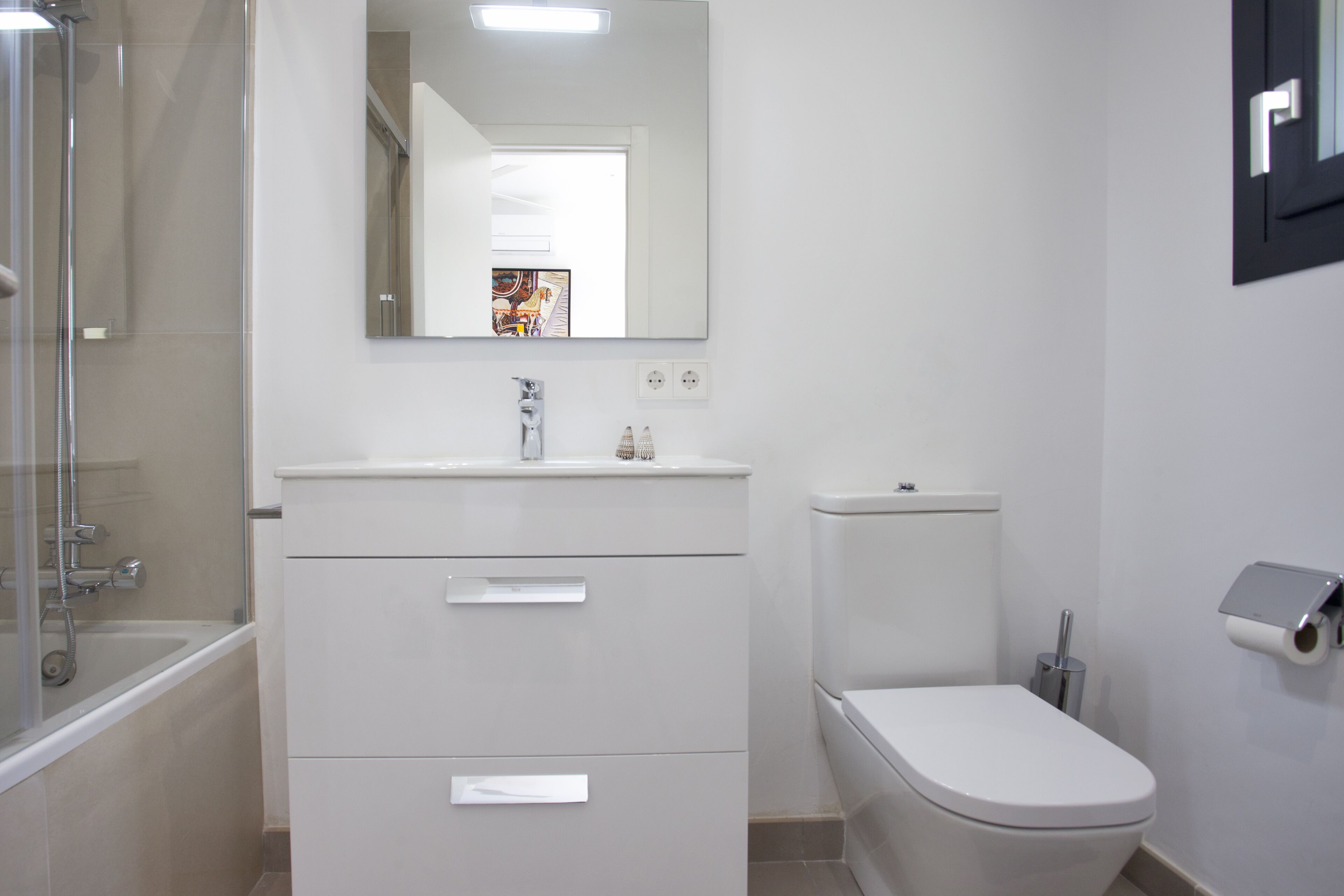 A modern bathroom with a bathtub, a toilet, and a vanity with drawers.
