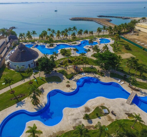 Vista aérea de un resort con varias piscinas, palmeras y una zona de playa.