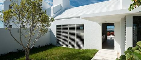 A modern white house with a clear view of the ocean through the doorway.