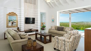 Un salón amplio con televisor grande, asientos cómodos y vistas al paisaje.