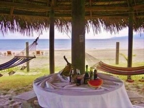 Escena costera con una mesa para dos, una hamaca y vista al mar.