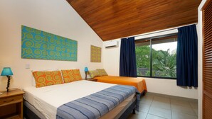 A bedroom with two beds, a nightstand, a lamp, and a window with curtains. - Only 350 meters from Tamarindo beach and downtown. In quiet and safe area. 
 (Tamarindo)