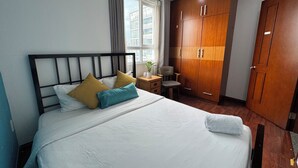 A hotel room with a bed, a desk, a chair, and a wardrobe.