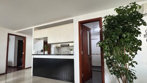 A spacious living area with a kitchen, a potted plant, and a tiled floor.