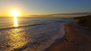 A beach with a sunset, waves, and a clear sky. - Honeymoon Bungalow in Banana Beach with AC, High Speed Wifi, Kitchen, Patio (Cobano)