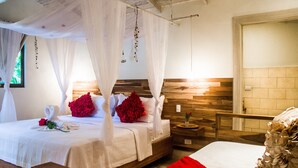 A four-poster bed with white linens, red pillows, and a red throw blanket. - Honeymoon Bungalow in Banana Beach with AC, High Speed Wifi, Kitchen, Patio (Cobano)