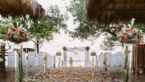A beach wedding setup with a decorated aisle, floral arrangements, and a thatched roof structure. - Honeymoon Bungalow in Banana Beach with AC, High Speed Wifi, Kitchen, Patio (Cobano)