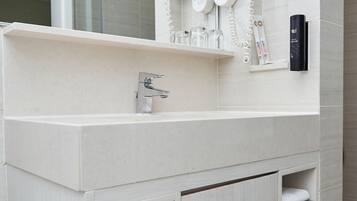 A modern bathroom with a white vanity, a large mirror, and built-in towel racks.