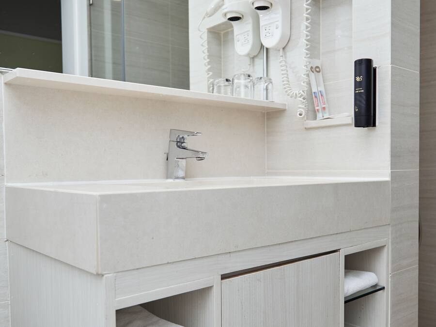 A modern bathroom with a white vanity, a large mirror, and built-in towel racks.