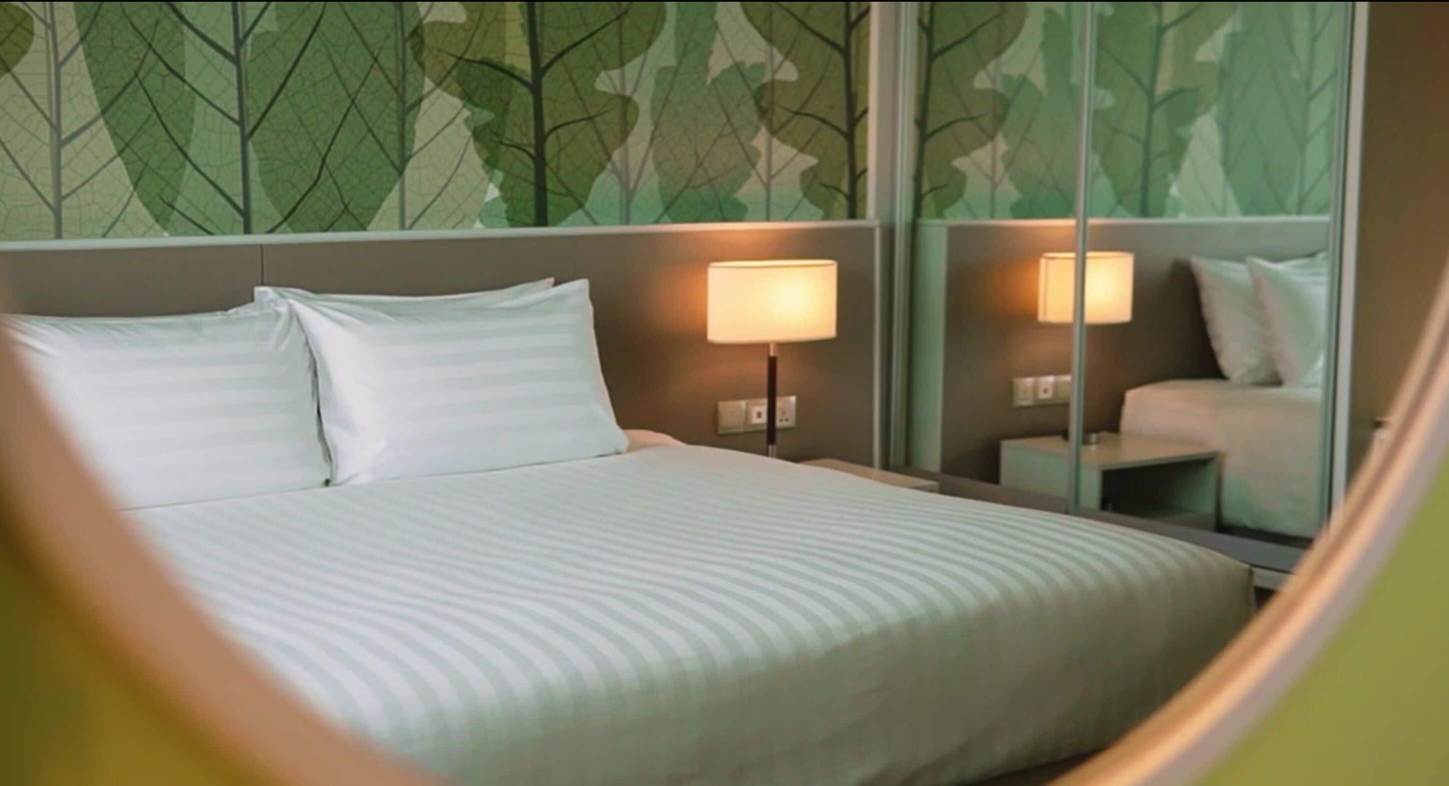 A hotel room with a bed, two bedside lamps, a nightstand, and a mirror.