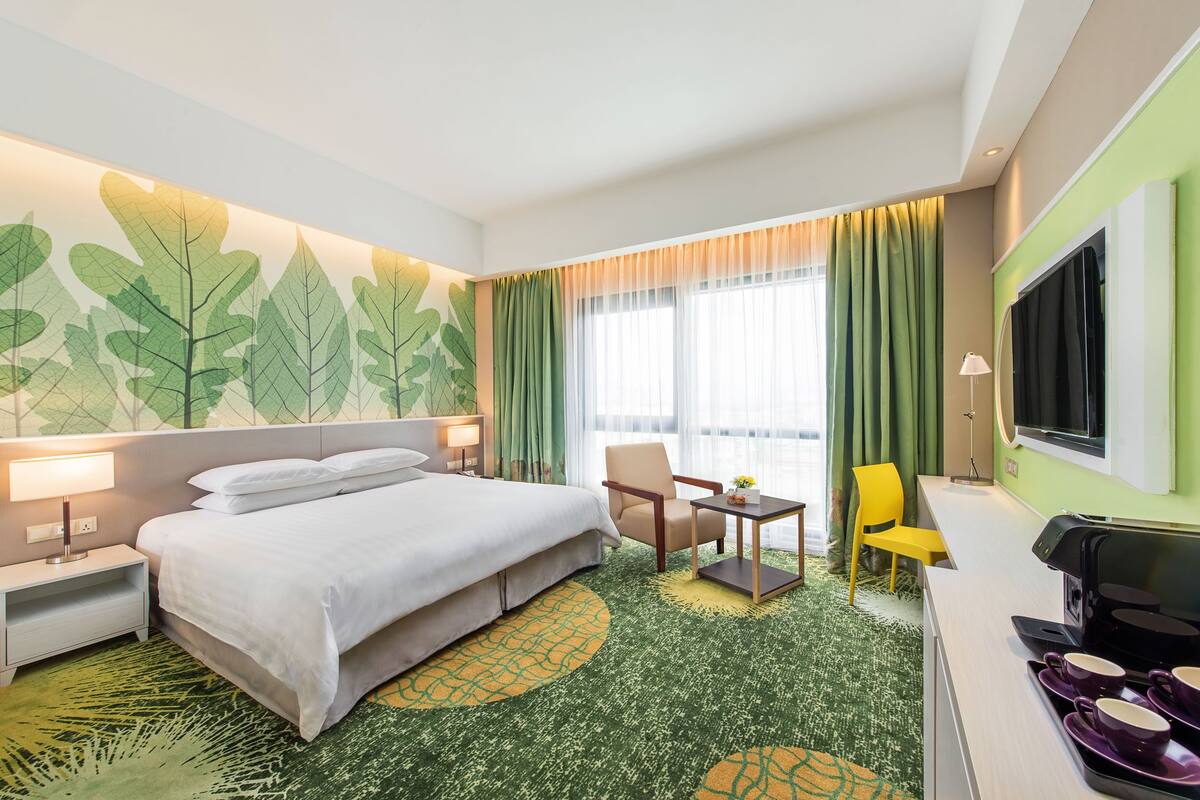 Een hotelkamer met een bed, bureau, stoel, televisie en koffiezetapparaat.