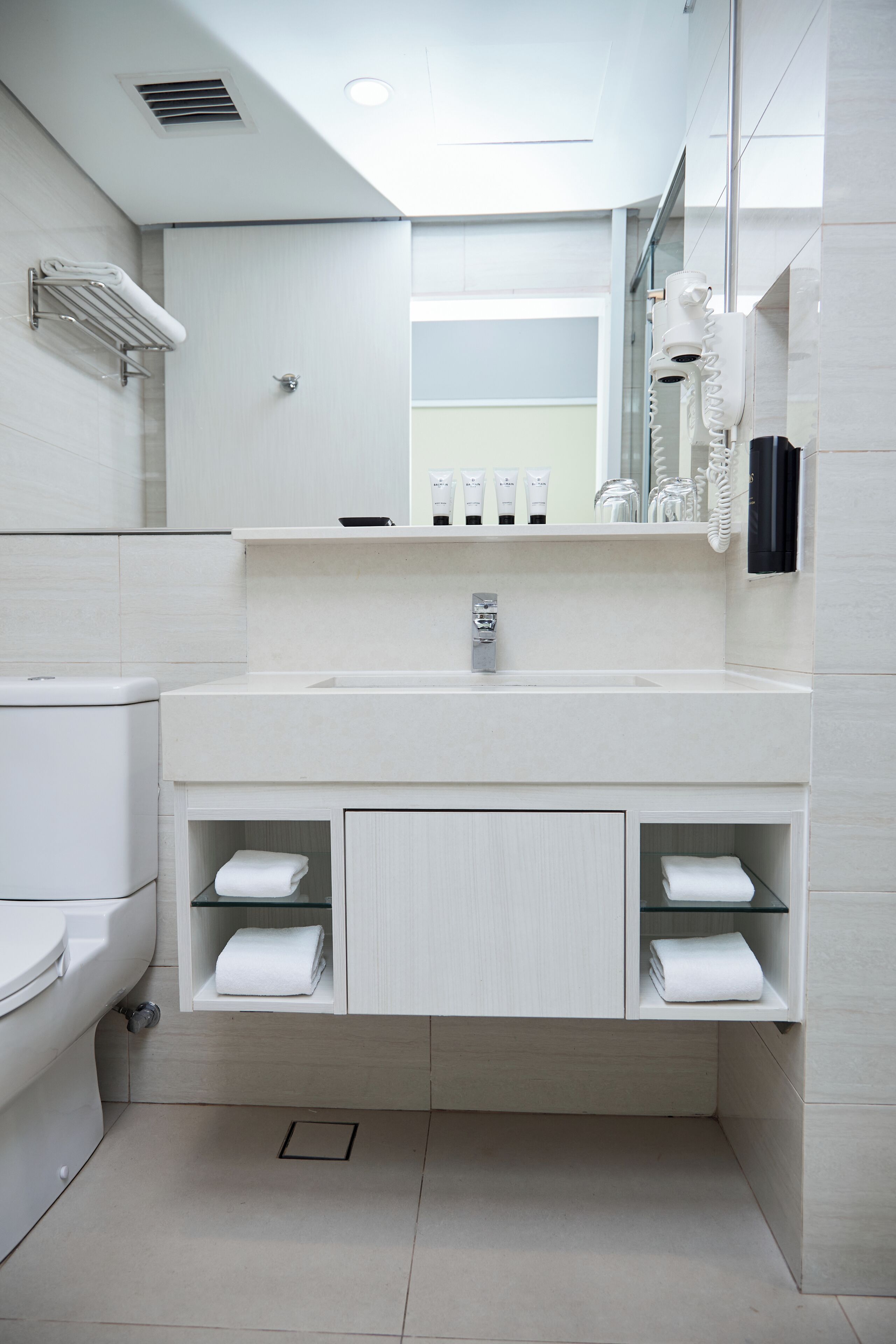 A modern bathroom with a white sink, mirror, and towel racks.