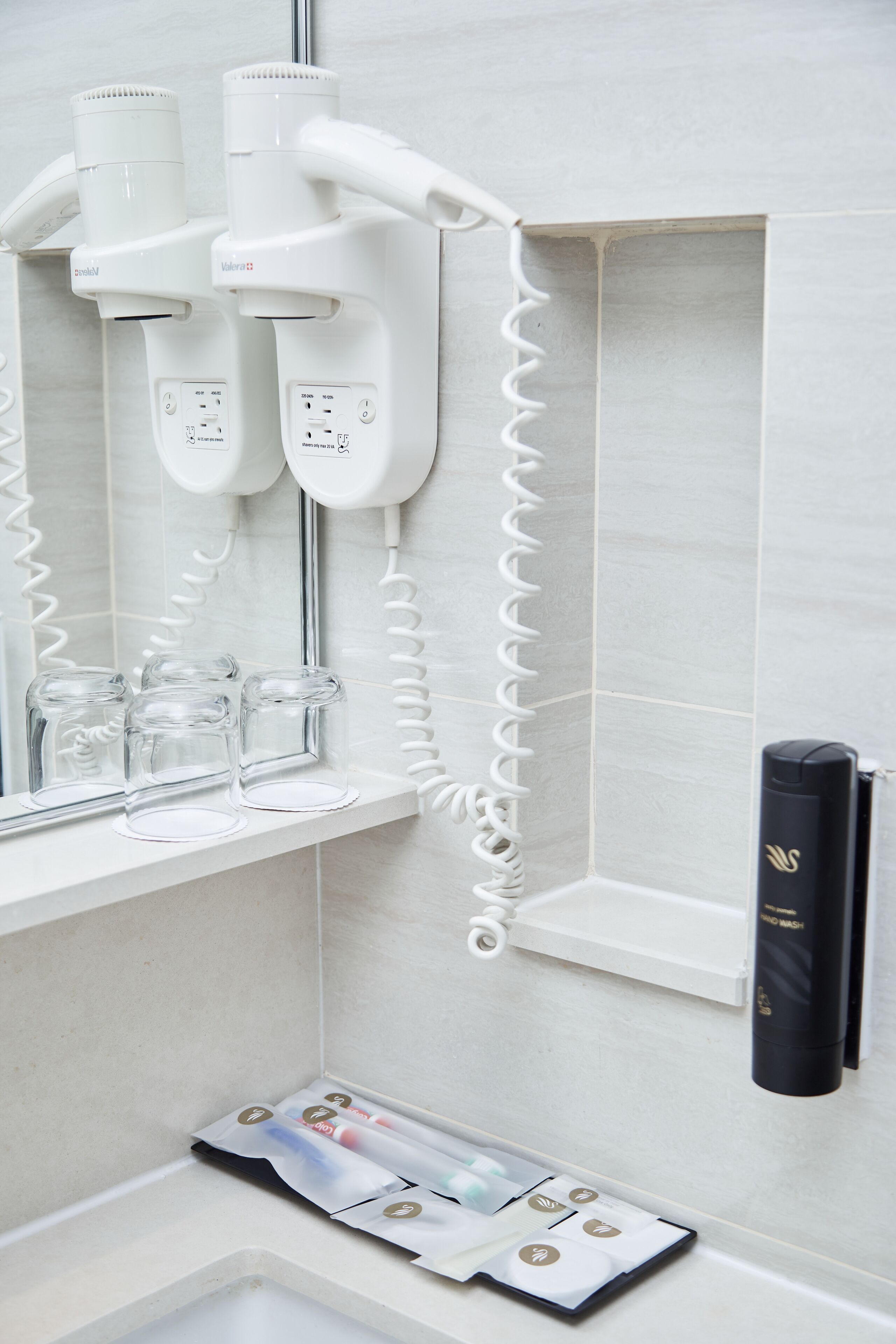 A bathroom with a hairdryer and a hand wash station.