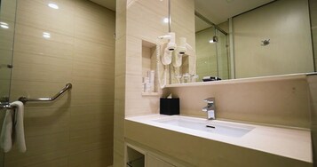 Un baño con lavamanos, espejo, toallero y secador de pelo.