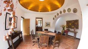 A dining area with a wooden table and chairs, a hanging terracotta pot decoration, and a ceiling with a wooden design. - Charming Home, Beautiful Decorated in famous Central Antigua  (Antigua Guatemala)