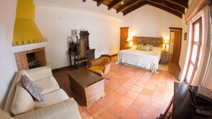 A cozy room with a fireplace, a bed, a sofa, and a wooden coffee table. - Charming Home, Beautiful Decorated in famous Central Antigua  (Antigua Guatemala)