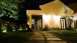 Ein modernes Haus mit gut beleuchtetem Eingangsbereich, einem Steinweg und einem Garten.
