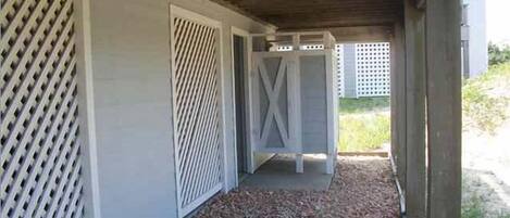 A covered outdoor area with a gravel path, white lattice panels, and a wooden structure.