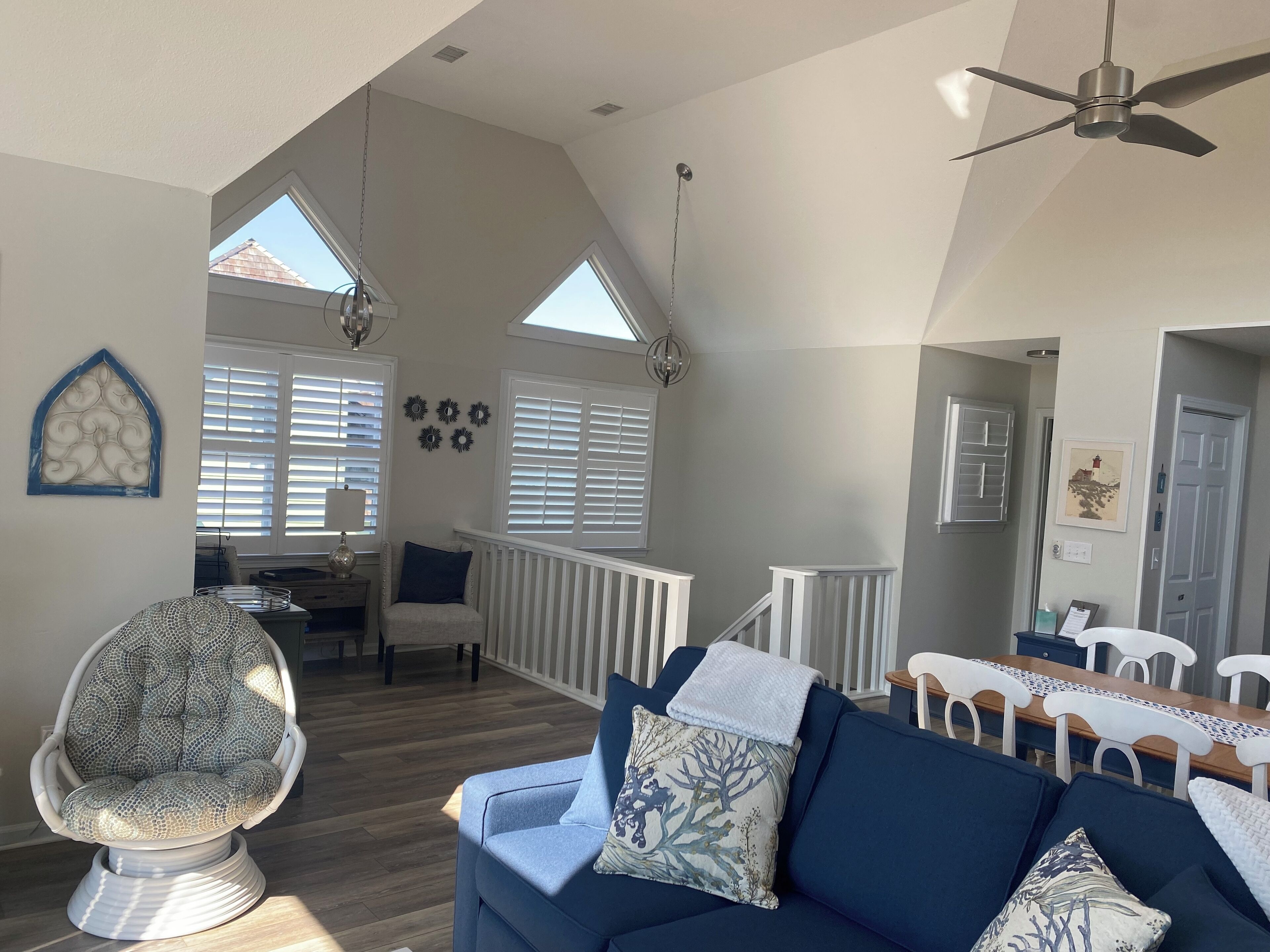 A spacious living room with a high ceiling, a ceiling fan, and a dining area with a wooden table and chairs.
