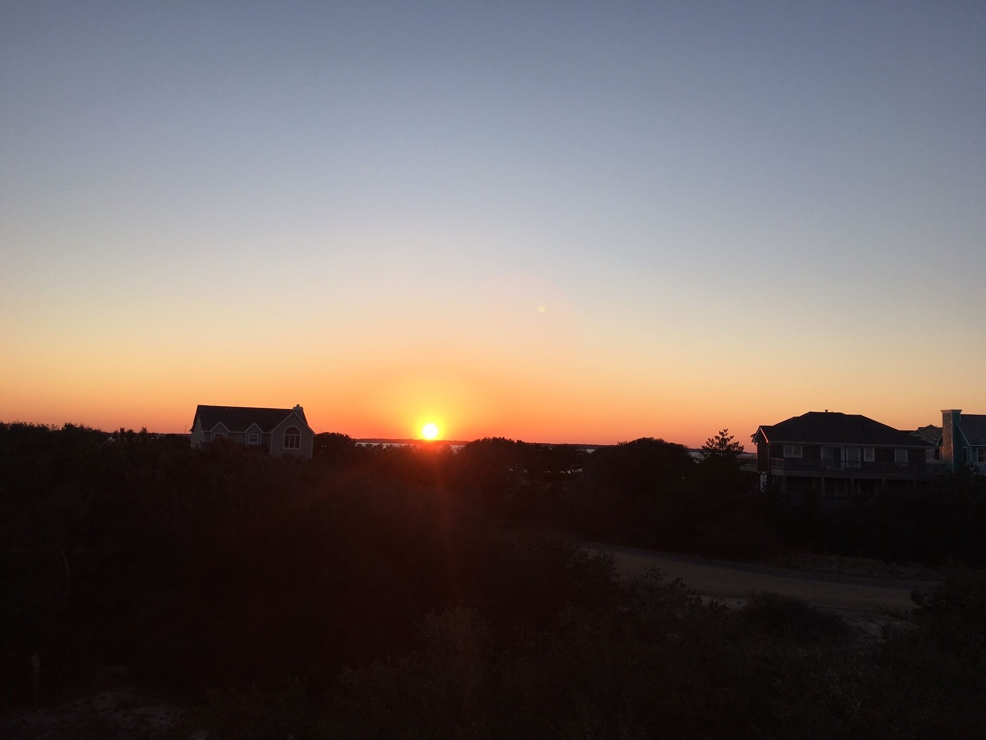 Atardecer sobre una zona residencial con casas silueteadas contra el cielo.