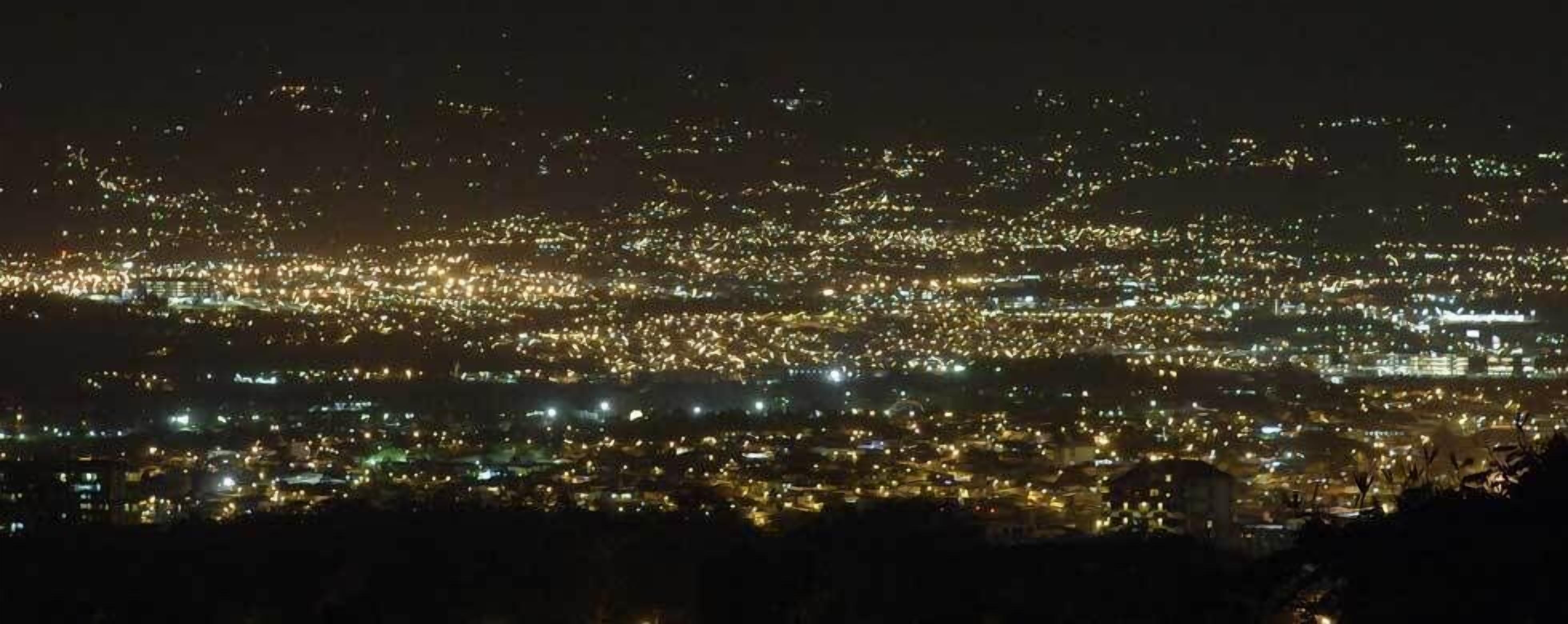 Een nachtelijke stadsgezicht met talloze lichtjes, wat wijst op een dichtbevolkt gebied.