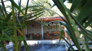 A pool area with stone walls and wooden furniture.