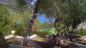 Un hamac attaché à un arbre, un mur de pierre et une étendue d’eau en arrière-plan.