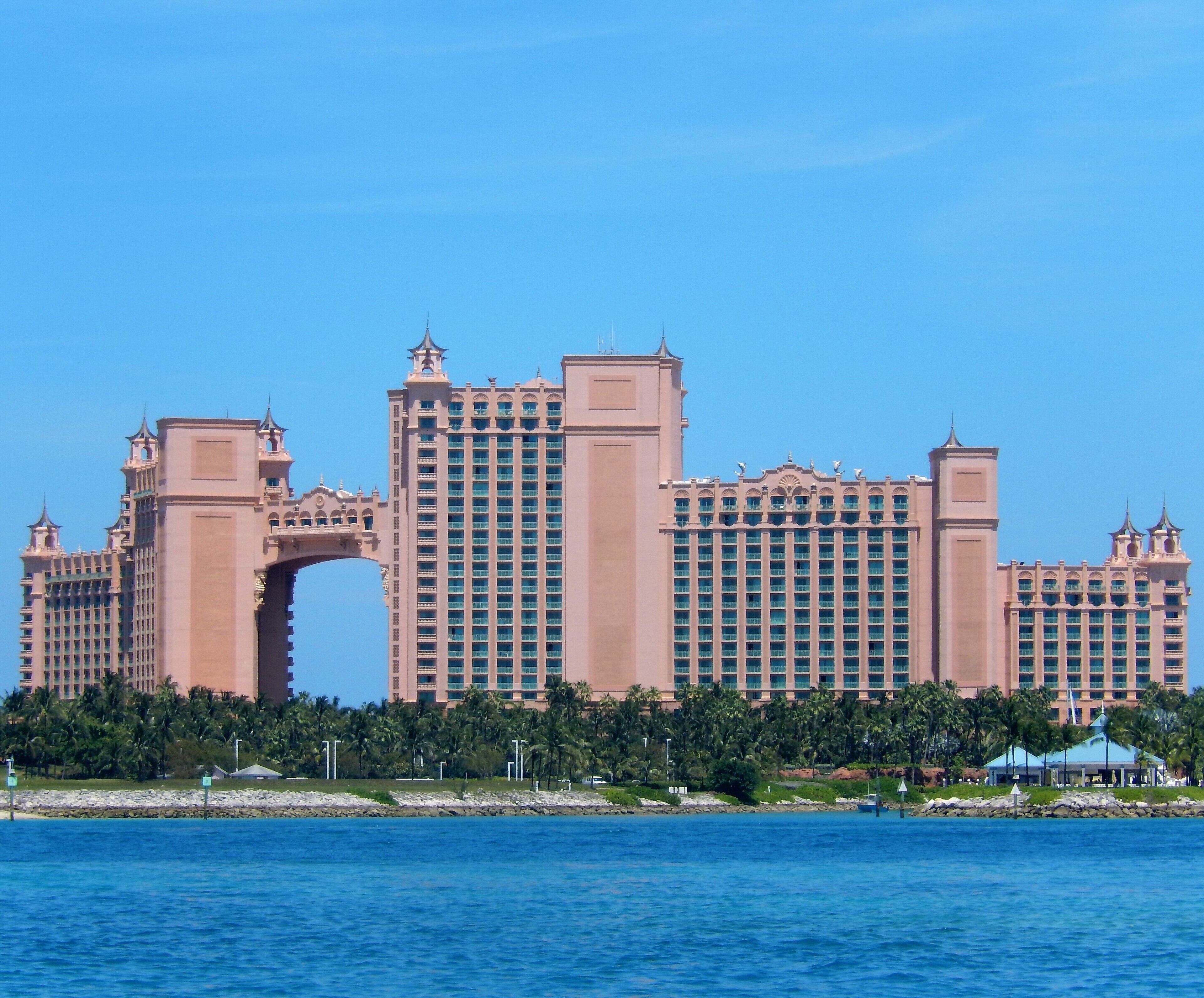 A large, multi-story hotel with a distinctive archway entrance, located near a body of water.