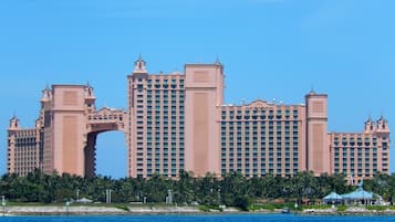 Un grand hôtel à plusieurs étages, doté d’une entrée remarquable en forme d’arc, situé près d’une étendue d’eau.