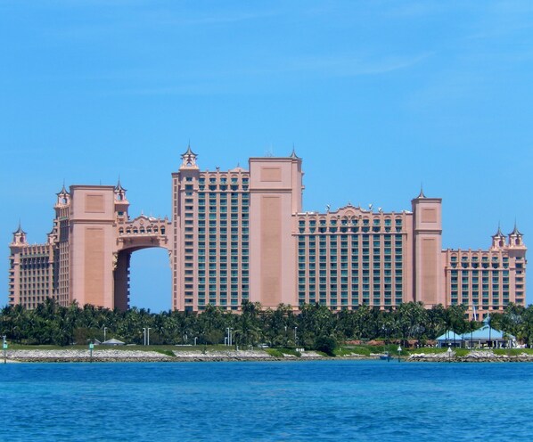 A large, multi-story hotel with a distinctive archway entrance, located near a body of water. - Paradise Island - Sunrise Beach Villa - Lowest Rates! (Nassau)