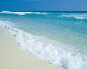Una playa con agua azul cristalina y arena blanca.
