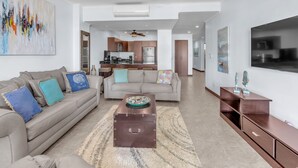 A modern living room with a sofa, coffee table, and a TV stand. - Oceanfront  Beachfront Condo Vacational Rental Jacó Beach Playa Jacó, costa rica (Garabito)