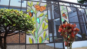 A mural with a butterfly and plant design on a building's exterior wall. - Oasis in Downtown next to Simon Bolivar Park with private balcony (San José)