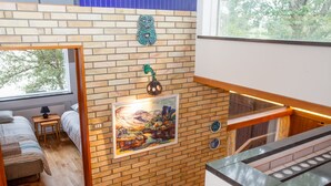 Une pièce avec un mur en briques, un tableau, une fenêtre et un lit.