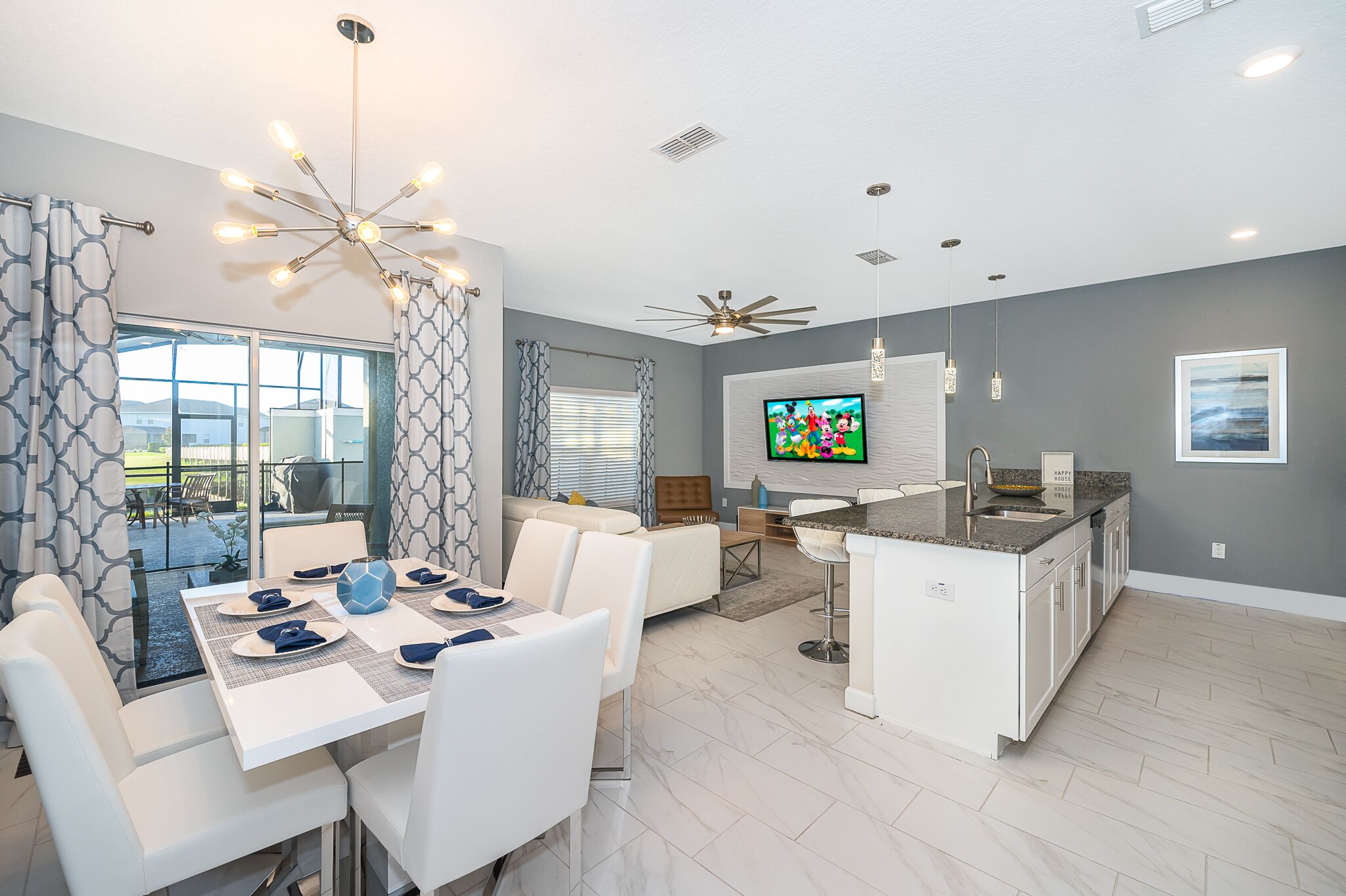 A modern kitchen with a central island, white cabinetry, and a dining area with a white table and chairs.