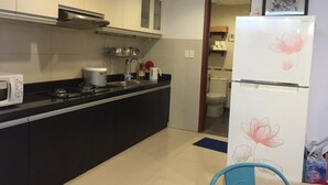 Une cuisine compacte équipée d’un four à micro-ondes, d’une cuisinière, d’un évier et d’un réfrigérateur orné de motifs floraux.