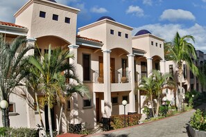 A row of beige buildings with arched balconies and a central courtyard.