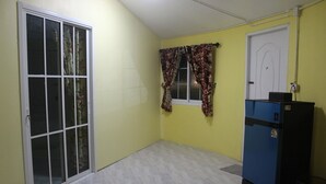 Una habitación con puerta de vidrio corredera, ventana con cortinas estampadas, una puerta y un armario azul.