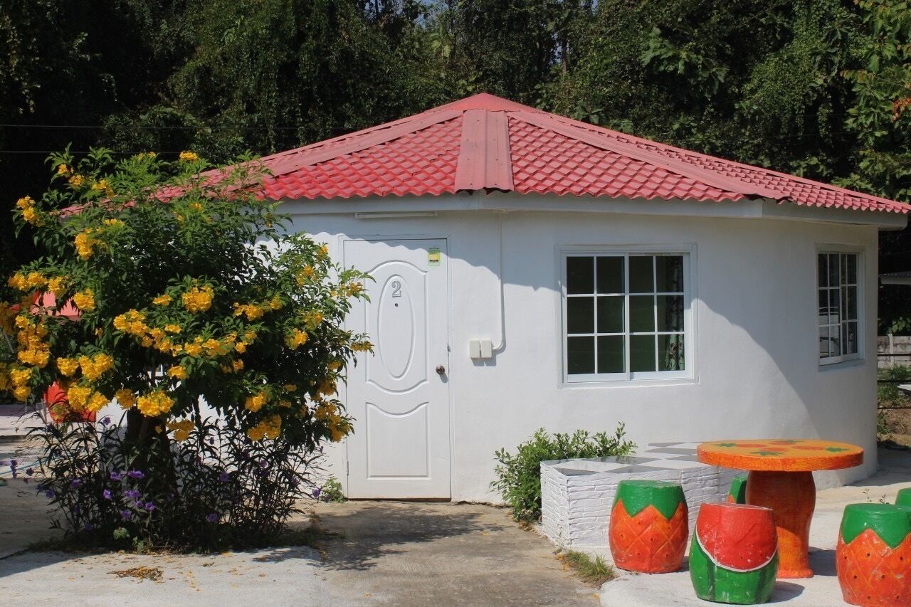 Um pequeno edifício branco com telhado vermelho, uma porta com o número 2 e uma janela.