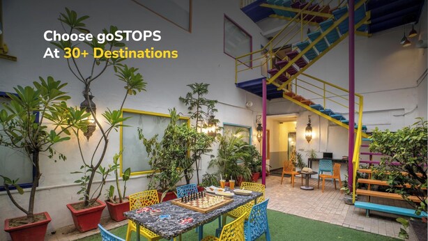 A cozy outdoor seating area with a chessboard, colorful chairs, and potted plants. - goSTOPS Delhi (New Delhi)