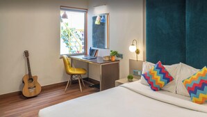 A cozy room with a bed, a desk, a chair, a guitar, and a window. - goSTOPS Delhi (New Delhi)