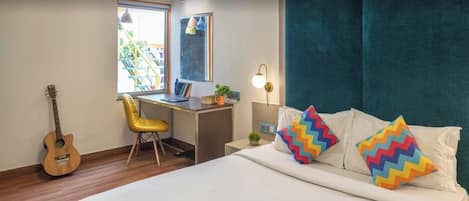 Una habitación acogedora con una cama, un escritorio, una silla, una guitarra y una ventana.