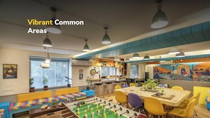A vibrant common area with a foosball table, colorful seating, and a mural. - goSTOPS Delhi (New Delhi)