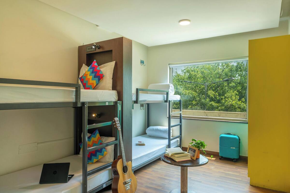 A bunk bed room with a laptop, guitar, and a suitcase.