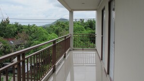 A balcony with a view of greenery and a distant hill. - AP Apartment (Si Racha)