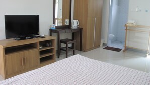 A bedroom with a bed, a TV, a desk, a wardrobe, and a bathroom. - AP Apartment (Si Racha)