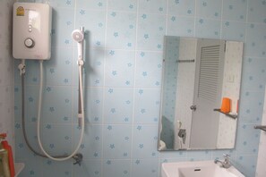 Un baño con ducha, lavamanos y espejo.