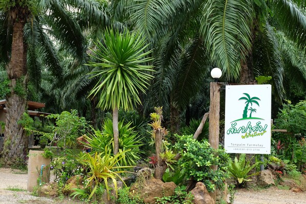 A sign for Tonpalm Farmstay with a tropical garden backdrop. - Tonpalm Farmstay (Khlong Thom)
