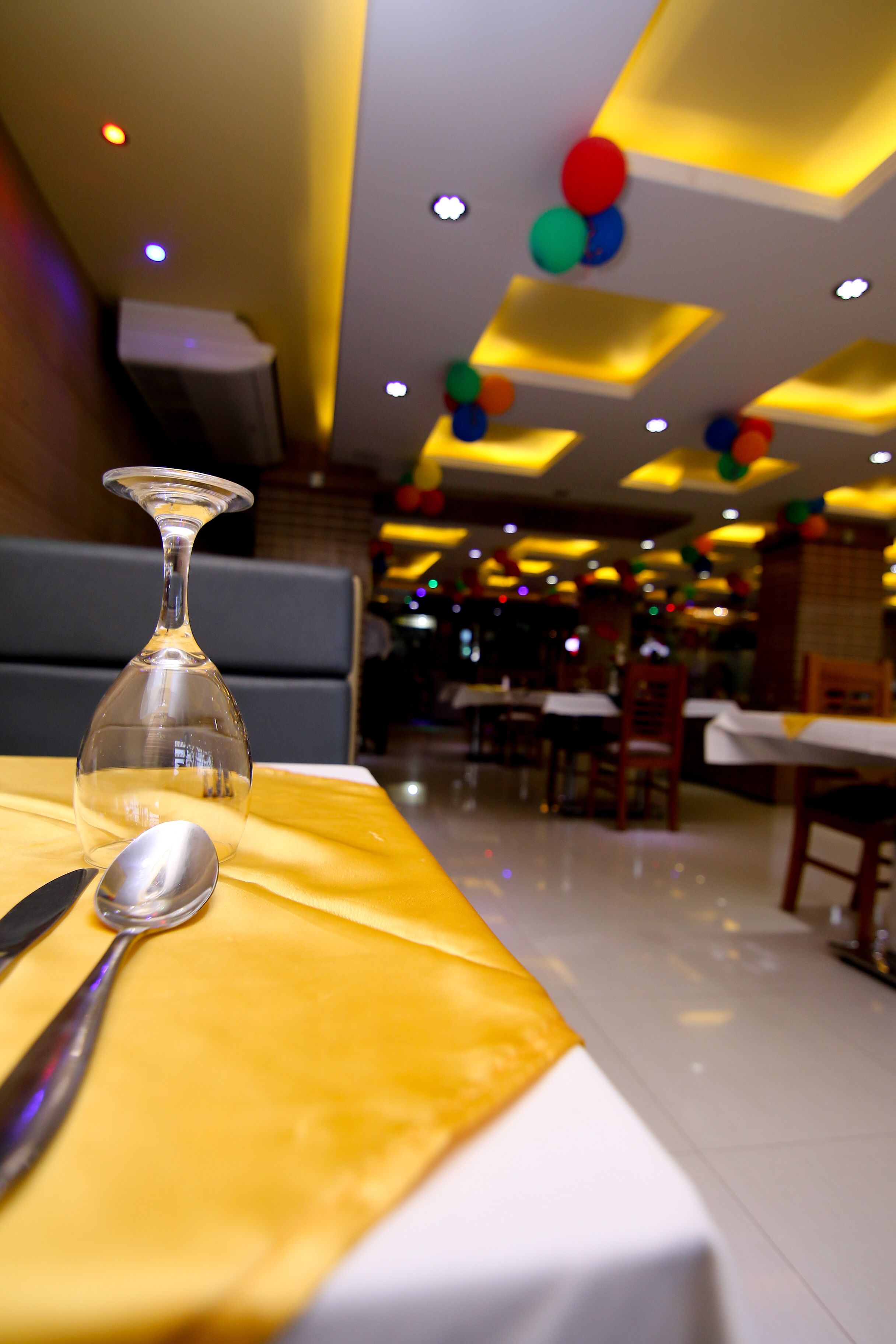 A restaurant setting with a table set for dining, featuring a clear wine glass and a spoon.