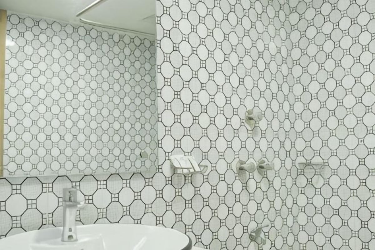 A bathroom with a hexagonal tile pattern, a white sink, and a mirror.